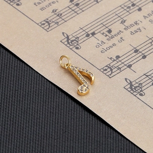 Macro shot of gold eighth note jewelry charm paved with crystals on vintage sheet music