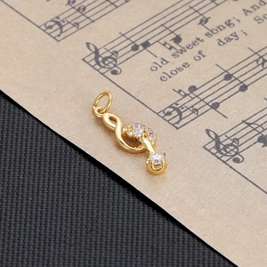 Macro shot of gold treble clef pendant with clear zircons on vintage sheet music