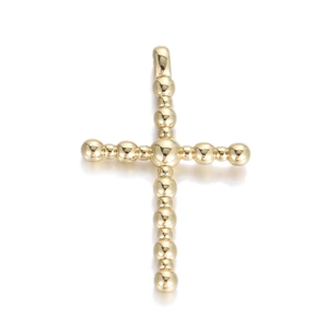 Detailed view of golden cross pendant with ball-beaded texture and polished metal finish