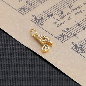 Macro shot of gold sixteenth note pendant with white rhinestones on vintage sheet music