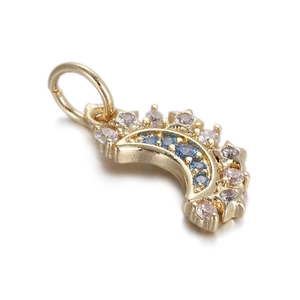 Macro shot of gold crescent moon pendant with inlaid blue and clear zircon stones