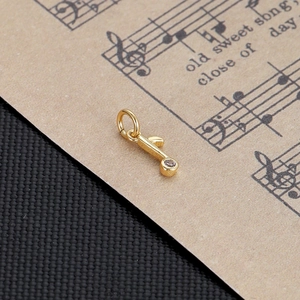 Detailed close-up of a gold music note pendant with crystal on vintage sheet music