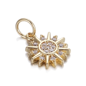 Macro shot of sun-shaped gold-plated pendant with clear crystals and a circular jump ring