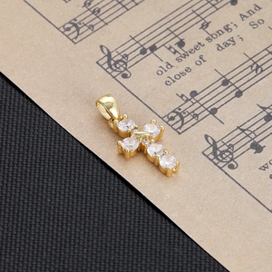 Close-up of golden cross pendant with six inlaid zircons on a sheet music background