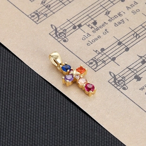 Detailed view of a gold cross pendant with colorful gemstones on a vintage music sheet