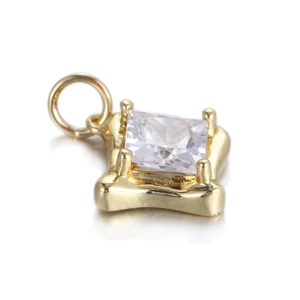 Close-up of gold cross pendant with square zircon inlay and polished metal finish