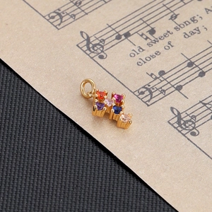 Close-up of golden cross pendant featuring vibrant colorful gemstones on music sheet