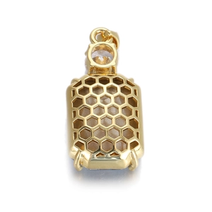 Détail macro du pendentif doré avec pierre claire et motif hexagonal en nid d'abeille au dos