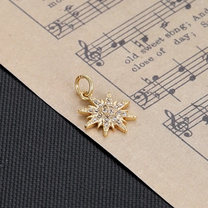 Detailed view of a gold starburst pendant with pavé zircons on vintage sheet music