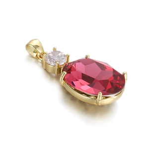 Vue macro du pendentif en zircon rouge ovale avec monture dorée et petit zircon blanc