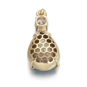 Vue macro du pendentif scarabée doré avec design alvéolé et pierre en zircone claire
