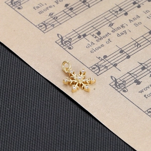 Close-up of golden snowflake pendant with white zircons on vintage music sheet background