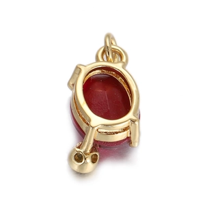 Détail d'un pendentif en pierre rouge ovale avec crâne doré et base plaquée or 18 carats