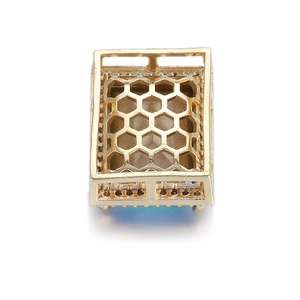 Détail du pendentif doré avec découpes en nid d'abeille et cristal bleu serti chic