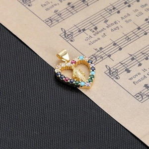 Detail of a golden heart pendant with colorful zircon stones and Virgin Mary carving