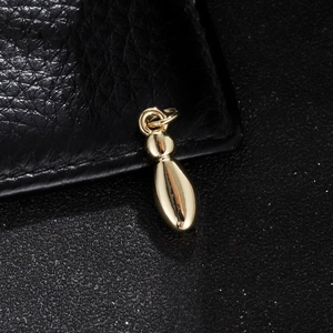 Close-up of polished gold balloon letter pendant on a black textured background