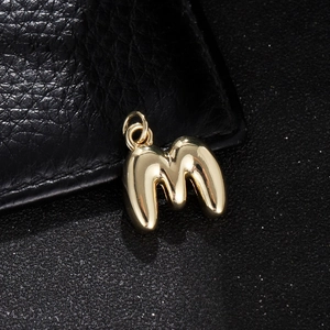 Macro shot of 3D puffy alphabet M pendant in 18K gold finish with high polished surface