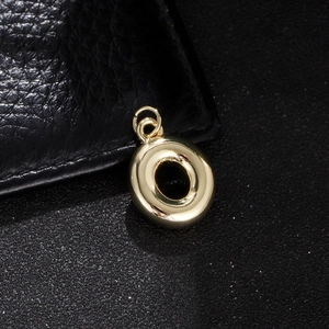 Macro shot of polished gold bubble letter O pendant with double metal jump rings