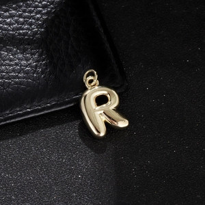 Detailed close-up of a glossy gold-plated bubble letter R pendant for DIY jewelry