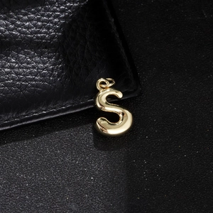 Close-up of a polished golden bubble letter S pendant charm with a high-shine finish