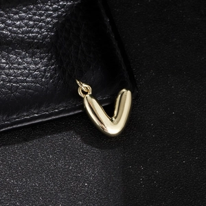 Macro shot of a 3D polished golden letter V pendant with a metallic bail and smooth edges