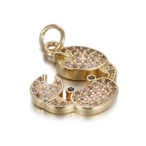 Detailed macro shot of a golden crab pendant with inlaid rhinestones on a white mirror