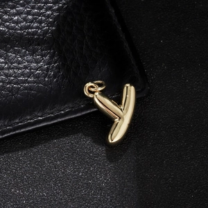 Detailed view of polished golden balloon letter y pendant on a textured black base