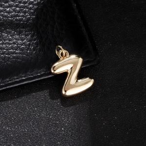 Close-up of a polished gold-plated letter Z balloon pendant with a double metal ring loop