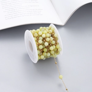 Detail of light green natural stone beads on a golden stainless steel chain for DIY jewelry
