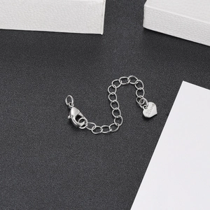 Macro detail of silver extender chain with lobster clasp and engraved heart charm