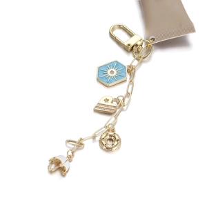 Porte-clés doré avec charms hexagone soleil, cœur, donut et parapluie sur fond blanc