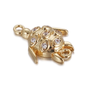 Detailed view of golden turtle pendant with inlaid zircons and double-loop design