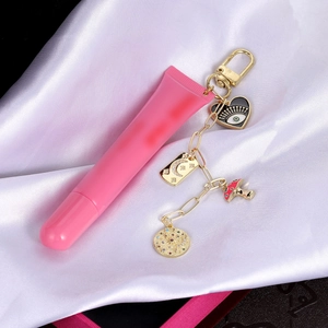 Detalle de llavero de lápiz labial rosa con dijes de esmalte sobre tela de satén