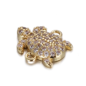Detailed view of turtle charm with pink crystals and gold base for jewelry making
