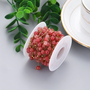 Detail of red stone beads and gold stainless steel chain roll for DIY jewelry making