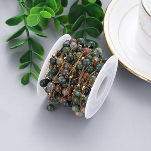 Macro shot of green stone bead chains wrapped on a spool for DIY jewelry crafts
