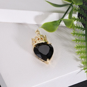 Macro shot of gold crown heart pendant with black zircon stone and white crystal inlay