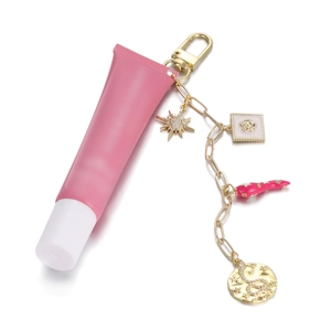 Llavero con colgante de tubo rosa, cadena dorada y dijes esmaltados sobre fondo blanco