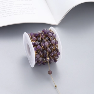 Detail of natural purple amethyst bead chain with gold stainless steel links on a spool