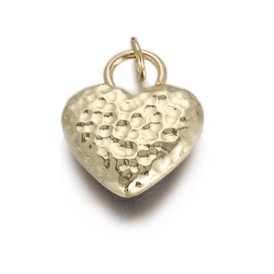 Macro shot of gold heart pendant with hammered texture finish and circular metal bail