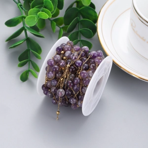 Detailed view of purple gemstone beads on a gold chain roll for DIY jewelry making