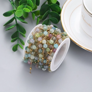Detail view of colorful natural stone beads and gold chain on a white spool