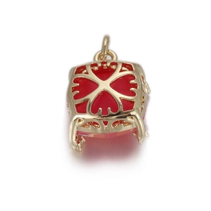 Macro detail of a hollow gold square pendant featuring a red heart stone and intricate patterns