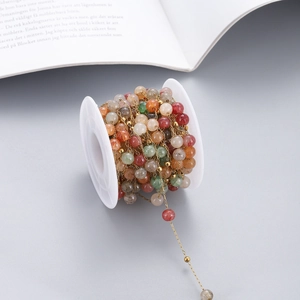 Detailed macro view of colorful natural stone beads on a golden chain spool for DIY jewelry