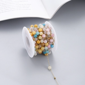 Colorful natural stone beads on golden stainless steel chain wrapped on a white spool