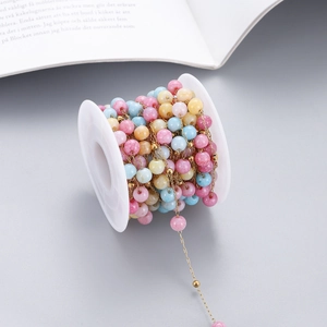 Detailed macro view of colorful natural stone beads on a golden DIY jewelry chain spool