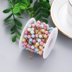 Detail of colorful stone beaded chain on a white spool for DIY jewelry making and crafts