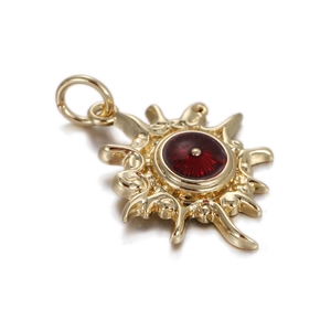 Detailed view of a gold sunburst pendant featuring a deep red circular center and ray design