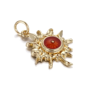 Detailed view of a gold sunburst pendant with a red enamel eye center and top bail