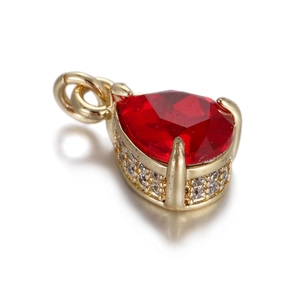 Vista macro de un colgante de gota dorado con piedra roja facetada y detalles de circonita
